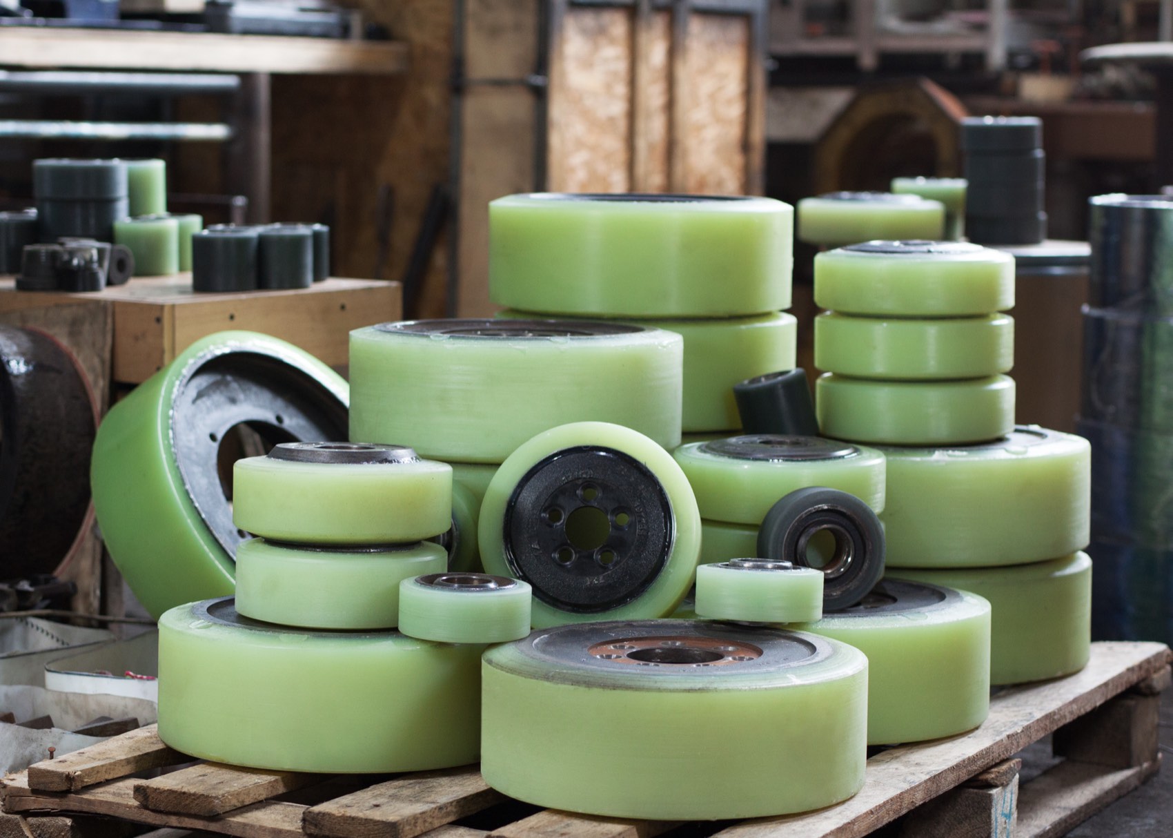 Freshly cast green polyurethane wheels stacked on a pallet in a workshop