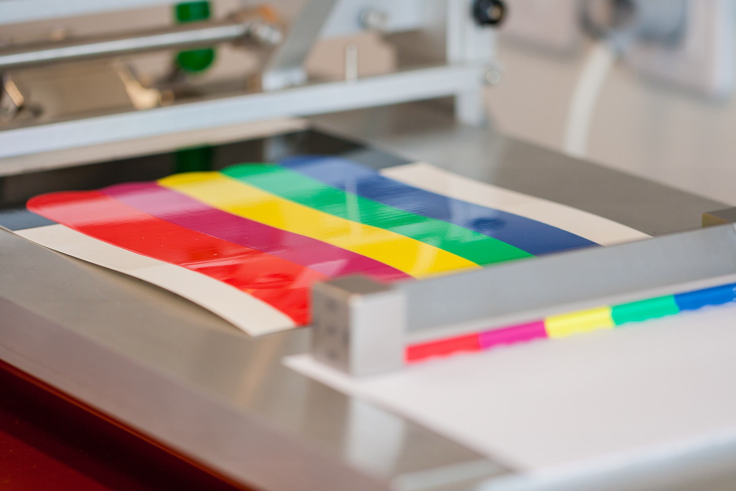 A color drawdown strip on a lab applicator, with red, green, yellow, magenta and cyan bars drawn down on white card