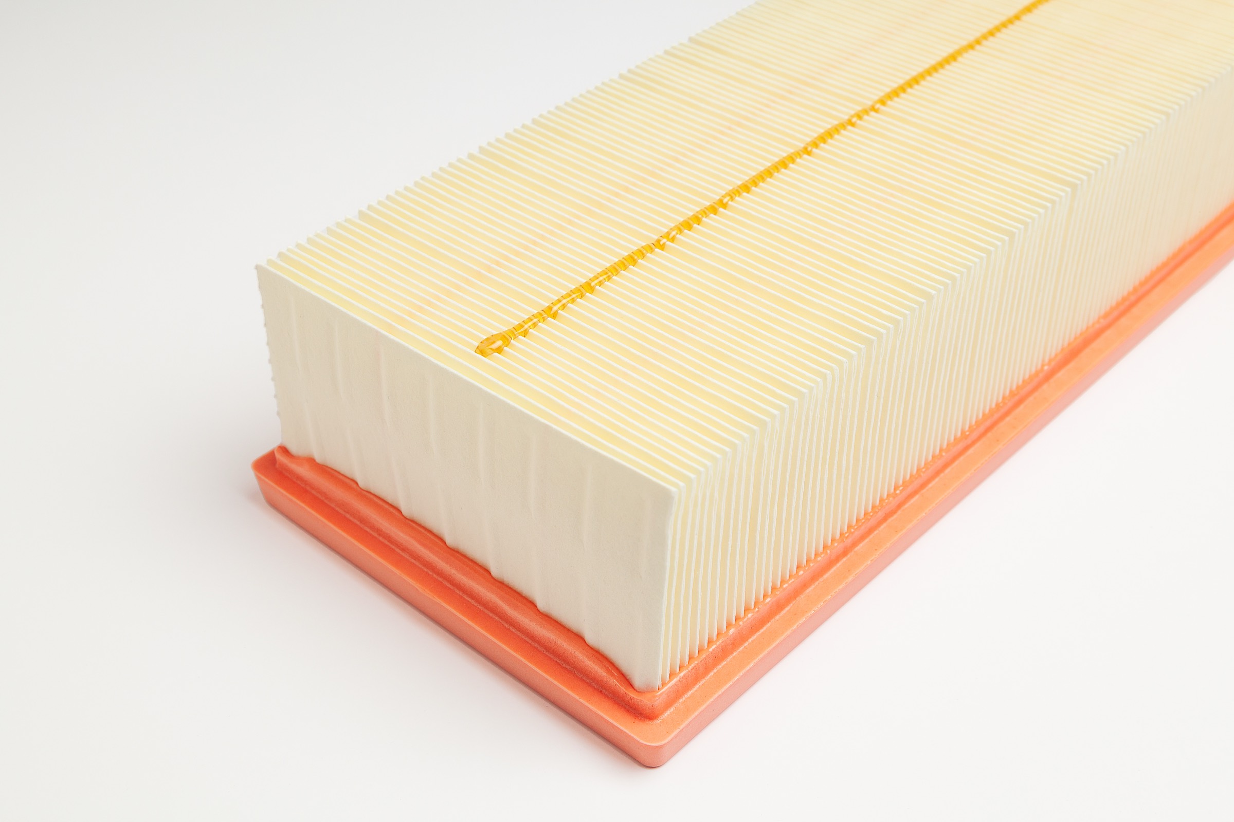 Pleated automotive engine air filter with an adhesive bead along the pleats