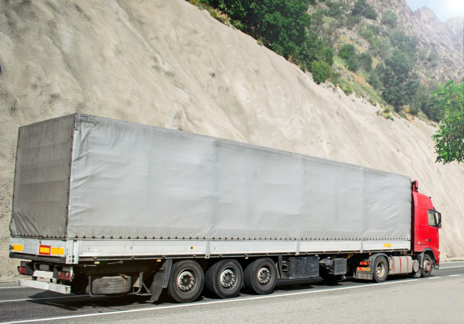 A grey tarpaulin curtain-side trailer on a road