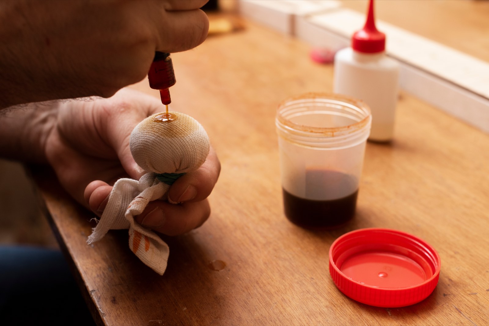 A craftsman charges a French-polish rubber with a shellac cut to build a hand-rubbed wood finish
