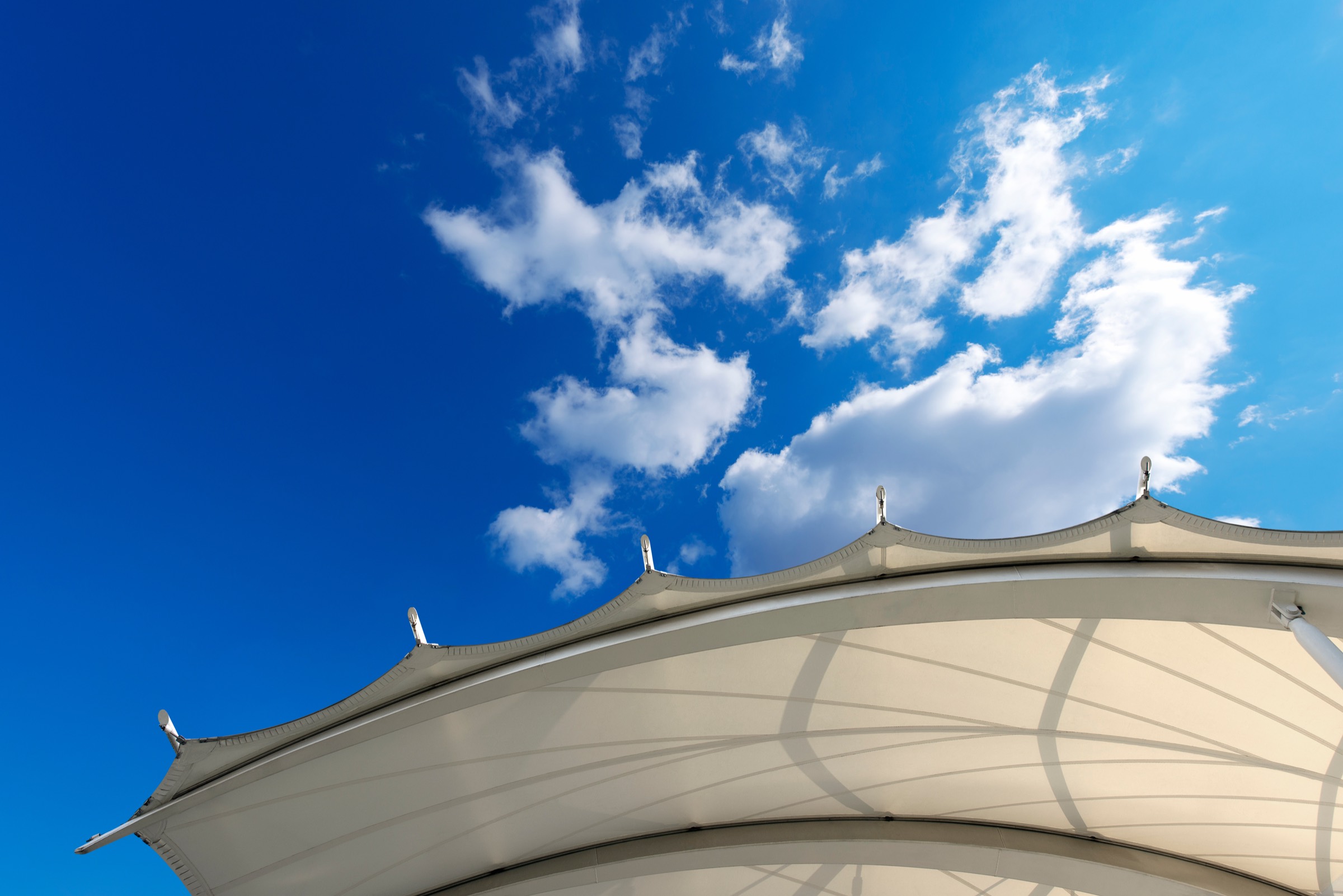 A white tensile membrane canopy against a blue sky