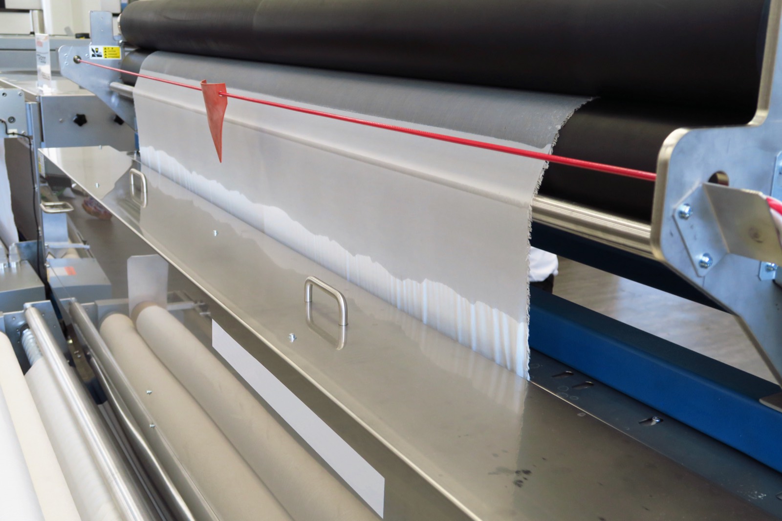 A coating line with the web running over a black roller under a red laser line