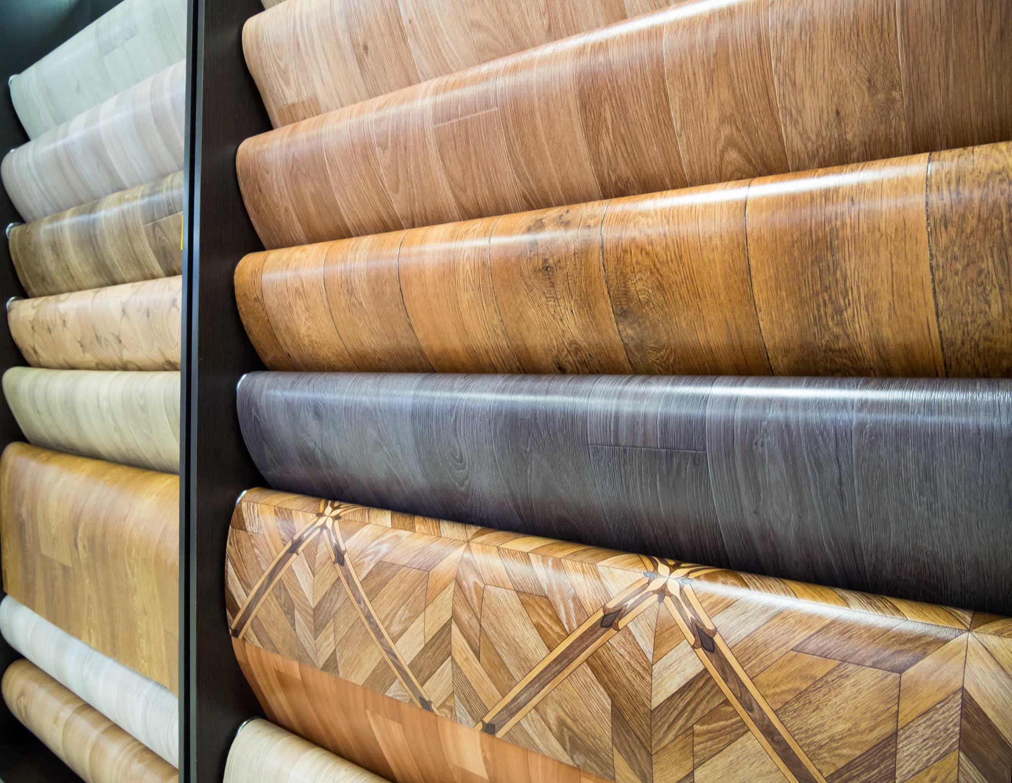 Rolls of wood-pattern resilient vinyl flooring stacked on a display rack